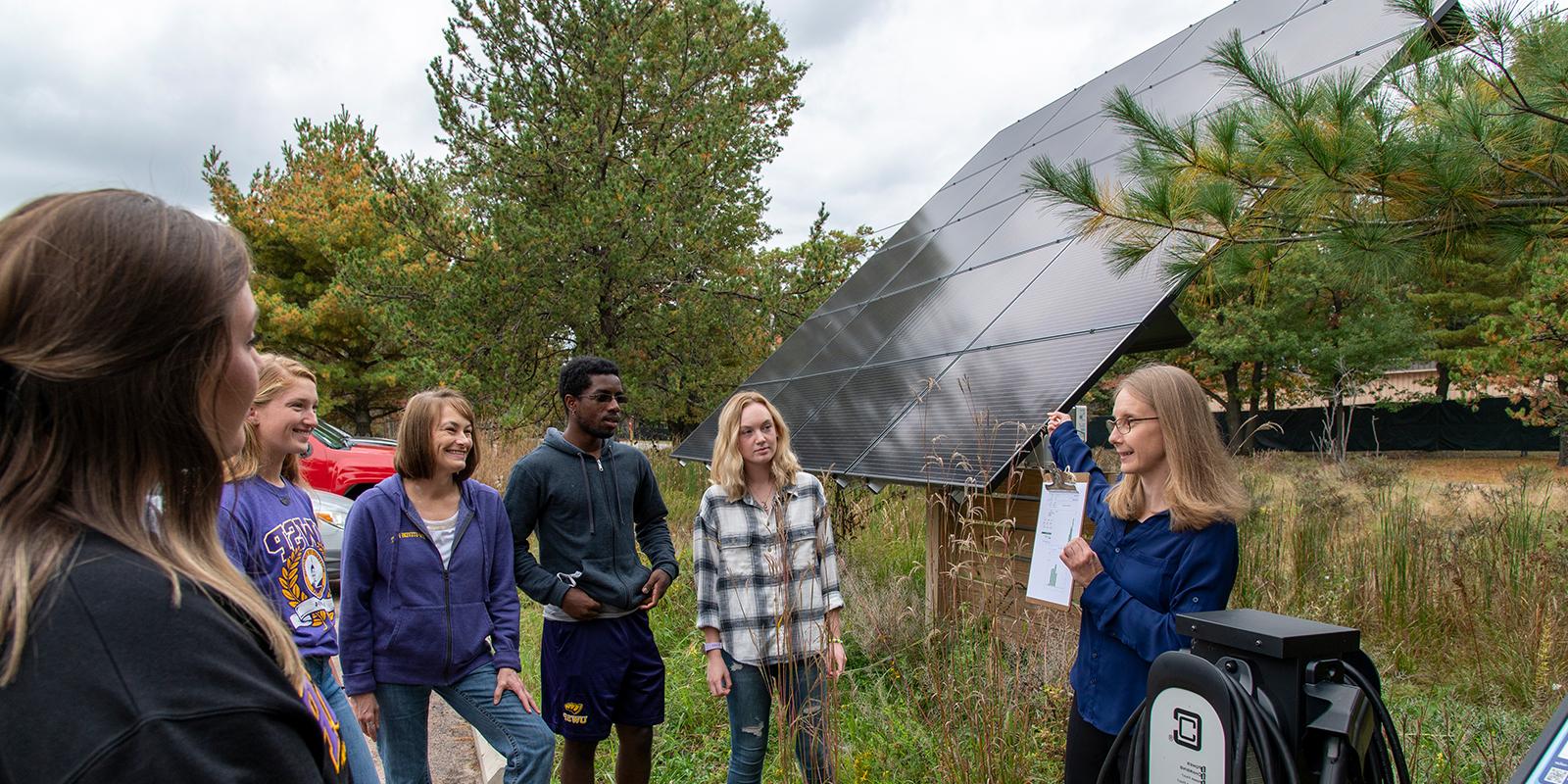 Professor and group of students looking at solar panel